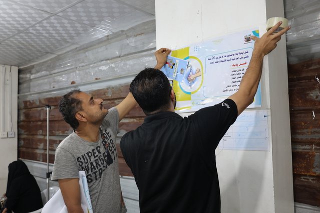 Gezondheidsvoorlichters hangen posters met hygiënemaatregelen op om de verspreiding van acute waterige diarree een halt toe te roepen.