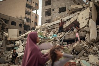 Een vrouw en haar kinderen zoeken naar hun spullen onder het puin in Gaza -Stad. © Motassem Abu Aser