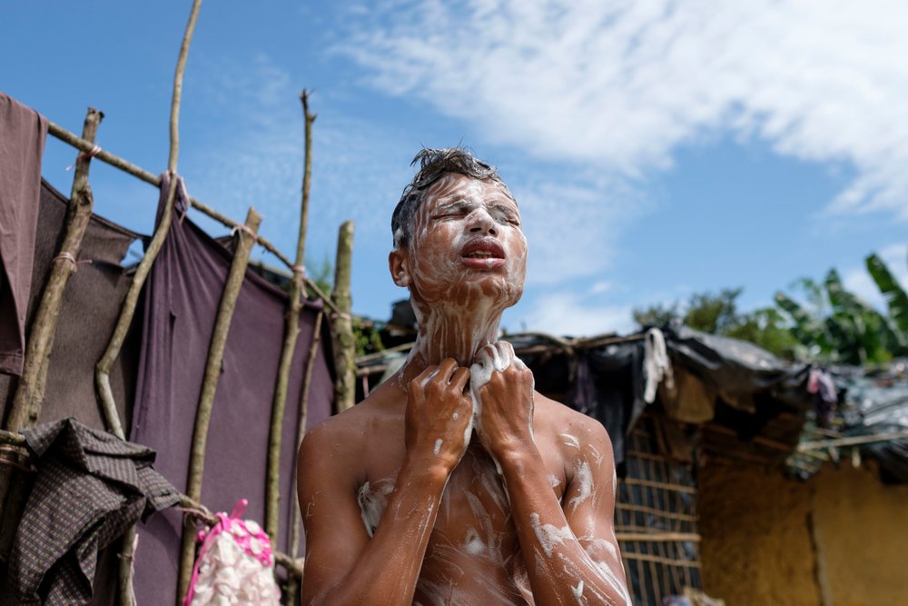 Een jongen wast zich in de buitenlucht in een vluchtelingenkamp in Bangladesh. © Antonio Faccilongo